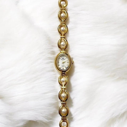 Veronoa Ilona Vintage Uhr mit goldenem Gliederarmband, Perlen-Details und ovalem Zifferblatt auf weißem Fellhintergrund.